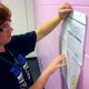 Allison Krecek from Downers Grove South tapes her dummy design to the classroom wall. The entertainment page features coverage about how the book Hunger Games is being made into a film. Krecek said the Writing and Design for Newspapers class, taught by Jody Mackey, is better than she anticipated because other similar classes she's taken at different workshops don't have the design component. ""It's definitely not something I expected this journalism class to do because (other classes) are usually all writing," she said. "I'm not a good drawer, but it's fun." By Jim Streisel / Upstart Staff